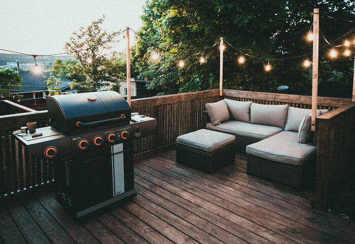 Black gas grill on brown wooden deck