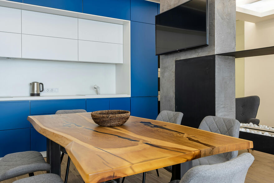 Big wooden table on the background of white and dark blue kitchen cabinets