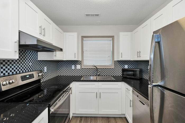 Kitchen with checkered pattern wallpaper and white cupboards