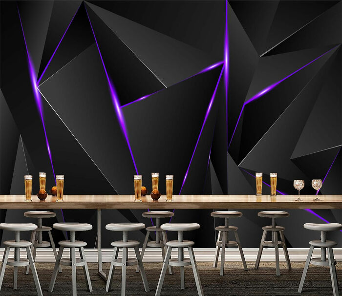 Room with dark geometrical with purple lines wallpaper and table with drinks and chairs