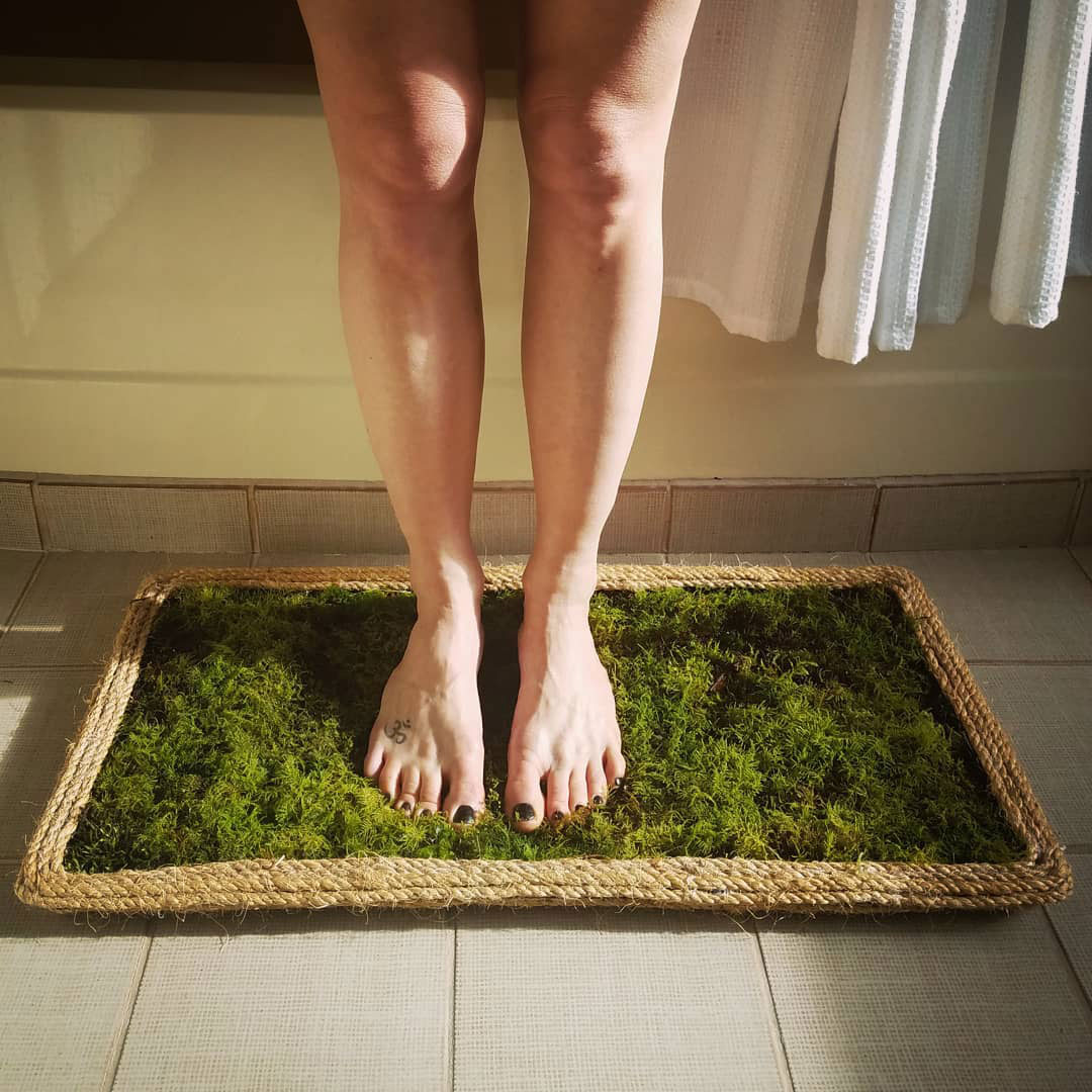 Women standing on natural moss bath mat.