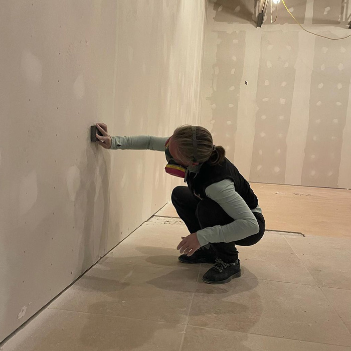 Woman sanding away at the wall