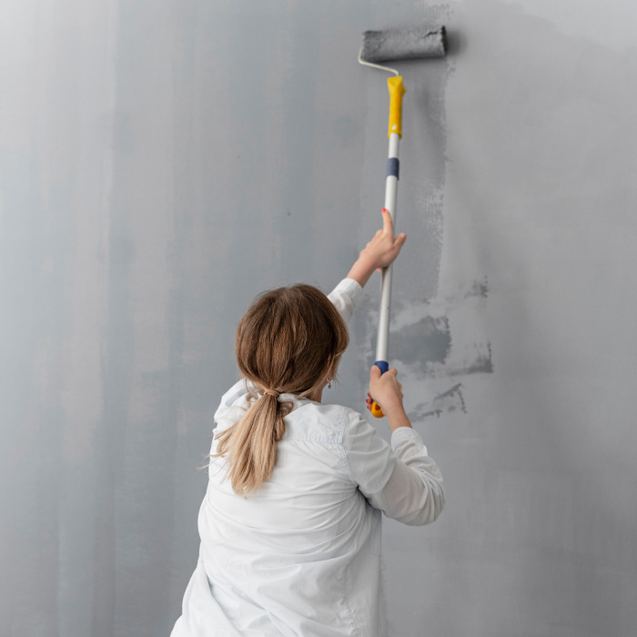 Woman painting a wall with roller 