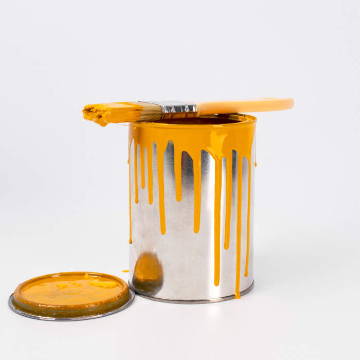 Open can with yellow paint, the brush on top of it 