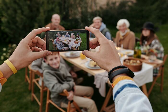 Person taking photo of family dinner on smartphone