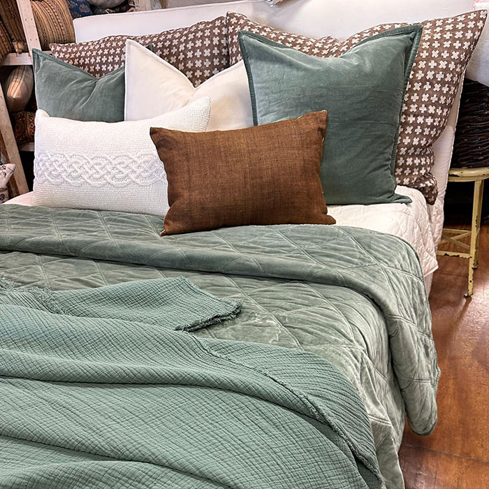 Sage green colored pillows and blanket on a bed
