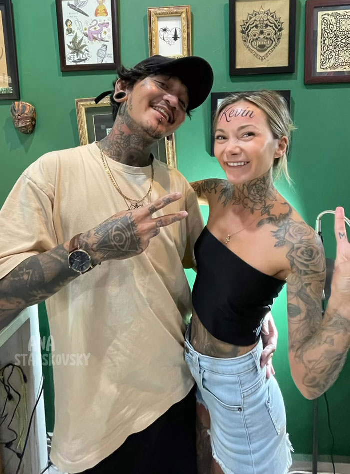 Influencer posing with “Kevin” inked on forehead, revealing it was fake, both smiling and surrounded by framed art. Influencer posing with “Kevin” inked on forehead, revealing it was fake, both smiling and surrounded by framed art.