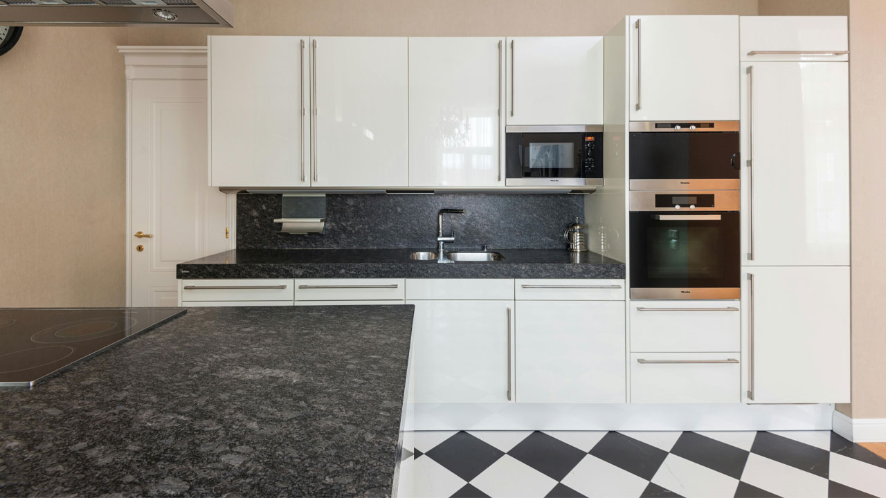 Image of a of white kitchen cabinets with black countertops.
