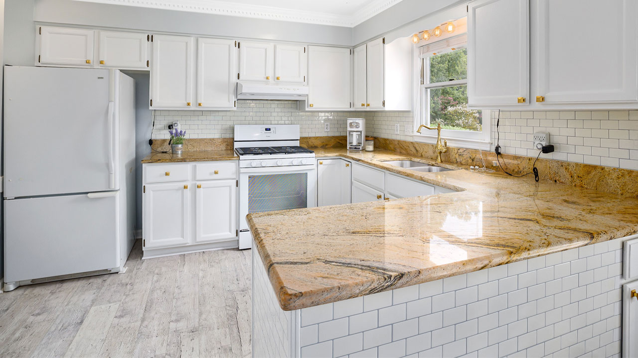 Image of a kitchen with white cabinets and granite countertops. 