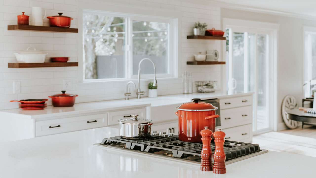 Image of a kitchen with white cabinets and red dishware.