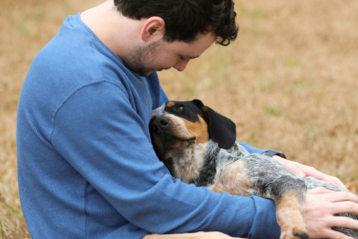 Man wearing blue shirt hugging a dog 