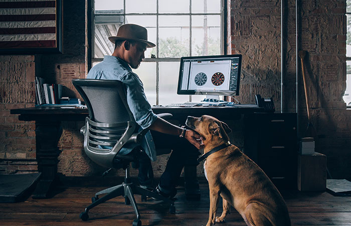 Man sitting near computer and petting dog.