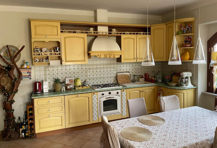 Dining table with tablecloth in the center of a muted yellow kitchen Dining table with tablecloth in the center of a muted yellow kitchen