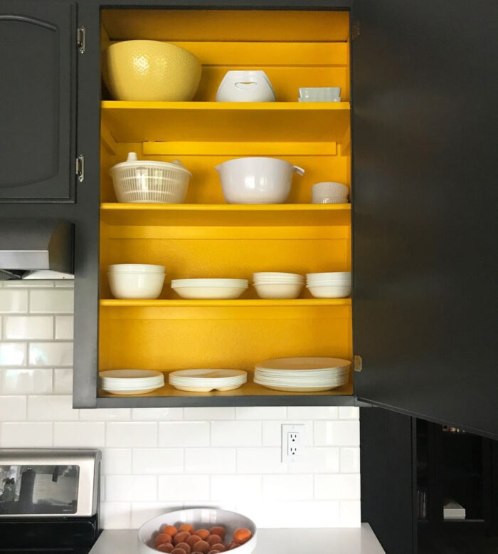 Black cabinet with painted in yellow shelves inside