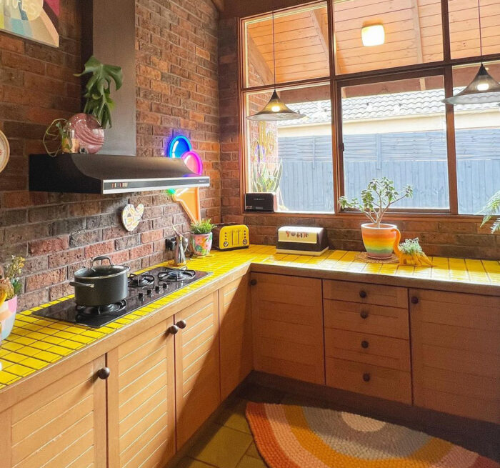 Kitchen with big window and yellow table top near the brick wall