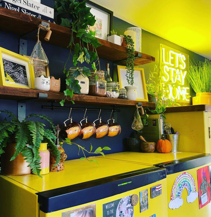 Shelves with kitchen items on the black wall near the yellow cabinets Shelves with kitchen items on the black wall near the yellow cabinets