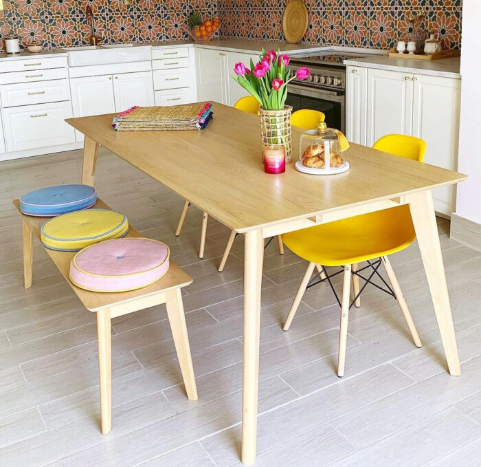 Dining table with yellow chairs and the bench with pillows