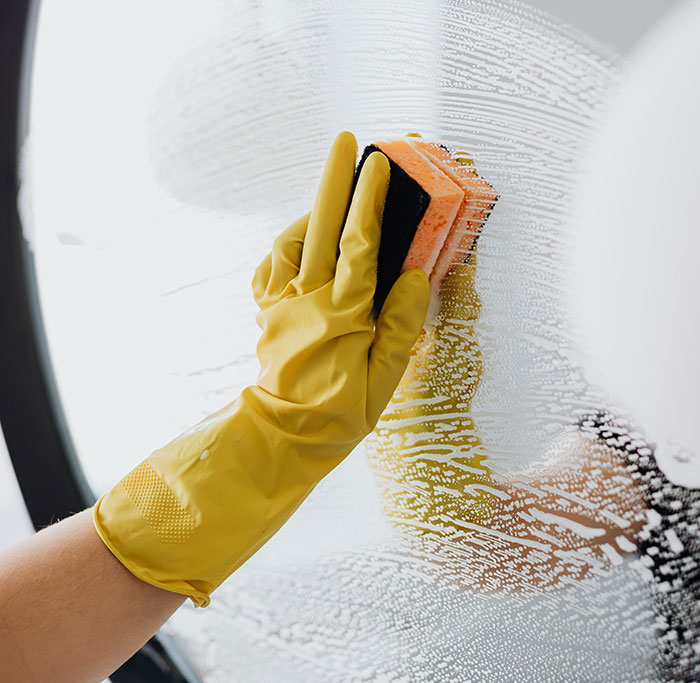 Person cleaning mirror with sponge