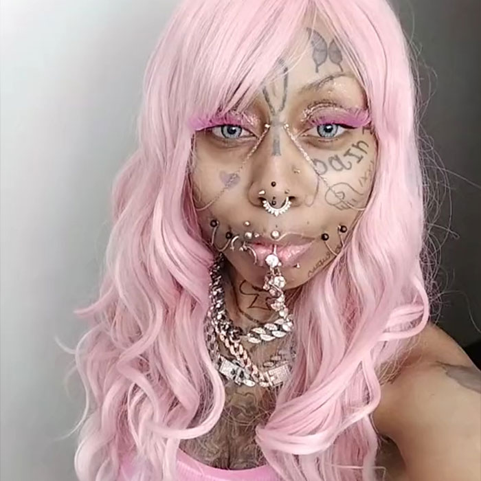 Inked grandmother, 41, with pink hair and facial tattoos, expressing confidence despite criticism. Inked grandmother, 41, with pink hair and facial tattoos, expressing confidence despite criticism.