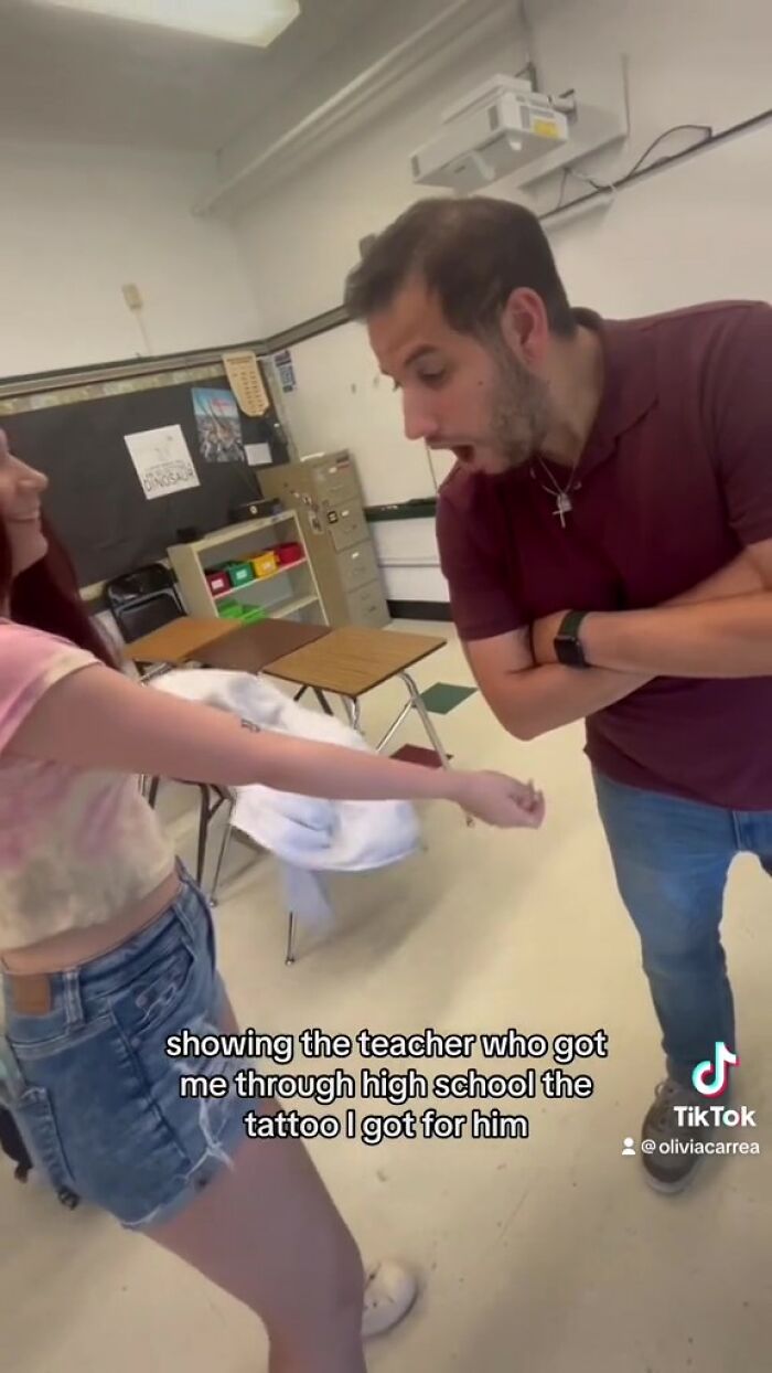 Student showing tattoo of teacher's handwritten note in a classroom, with teacher reacting in surprise. Student showing tattoo of teacher's handwritten note in a classroom, with teacher reacting in surprise.