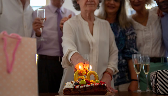 Elderly woman celebrating birthday with friends, cutting cake; longevity concept. Elderly woman celebrating birthday with friends, cutting cake; longevity concept.