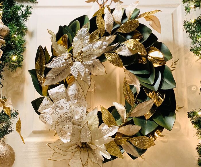 Christmas wreath with green and golden leaves and white flowers