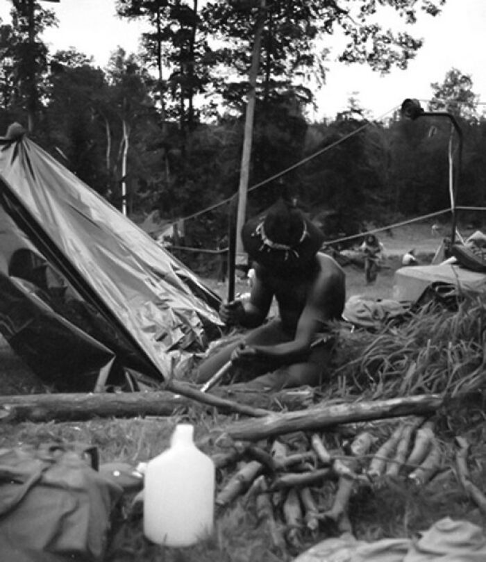 "Hippy" making a fire, camping on slopes of Powder Ridge ski area, during canceled Rock Festival, 1970