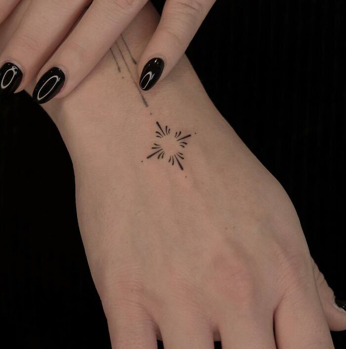 Black delicate ornament tattoo on the hand