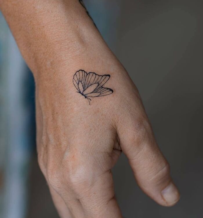 Black linear butterfly tattoo on hand