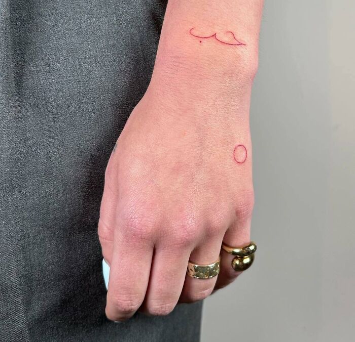 Minimal small red circle tattoo on hand
