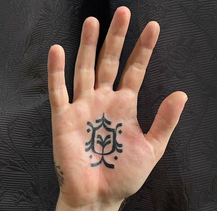 Black ornamental tattoo on hand palm