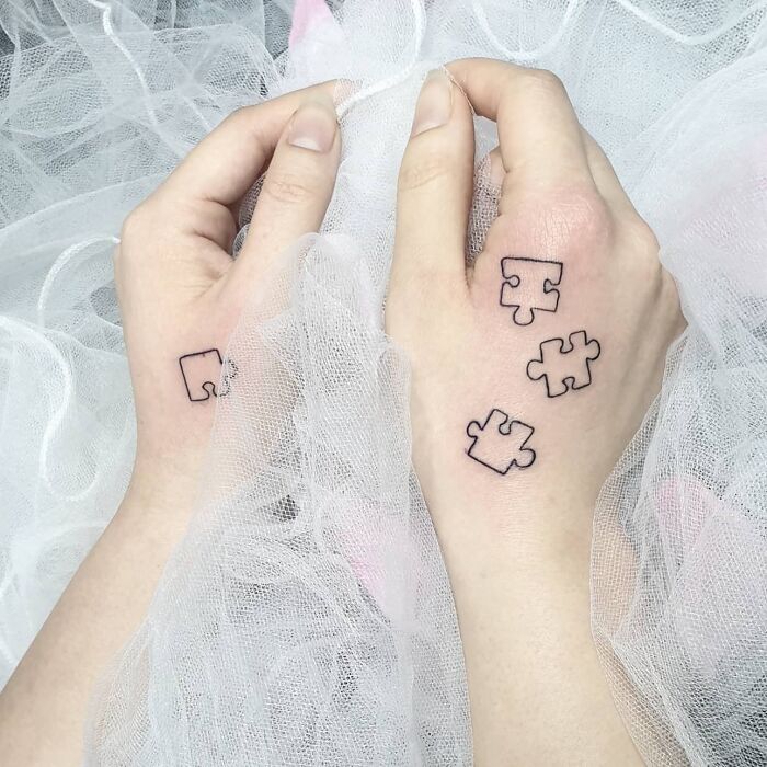Linear puzzle pieces tattoos on hands