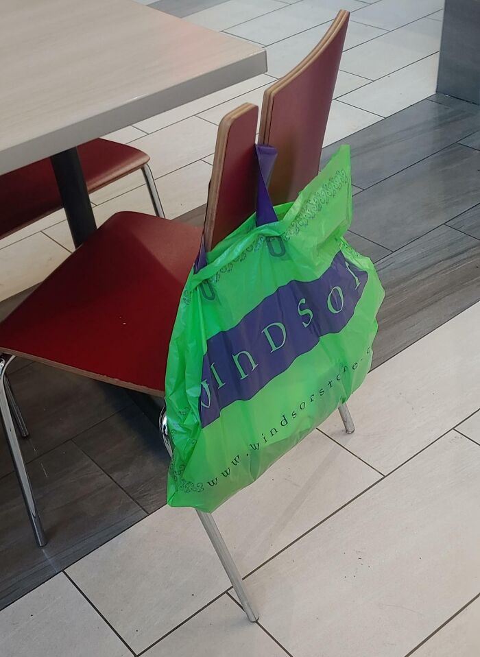 Esta silla en la zona de restaurantes de un centro comercial tiene esta muesca para colgar las bolsas