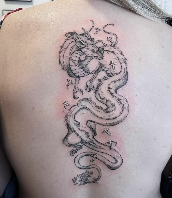 Detailed dragon spine tattoo with intricate line work, showcasing a creative design on the back.