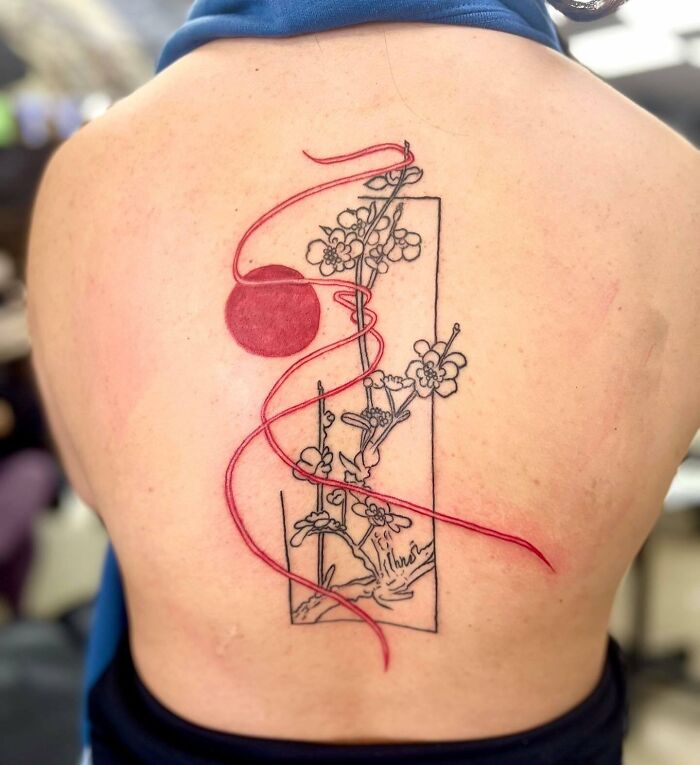 Red moon, string, and flowers in unfinished rectangle tattoo on back