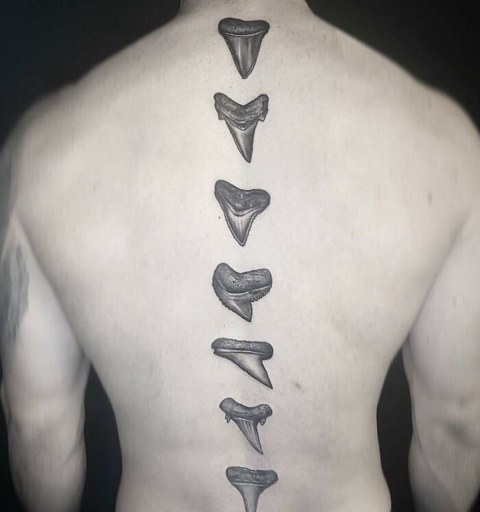 "Unique spine tattoo featuring vertical shark teeth design along the back."