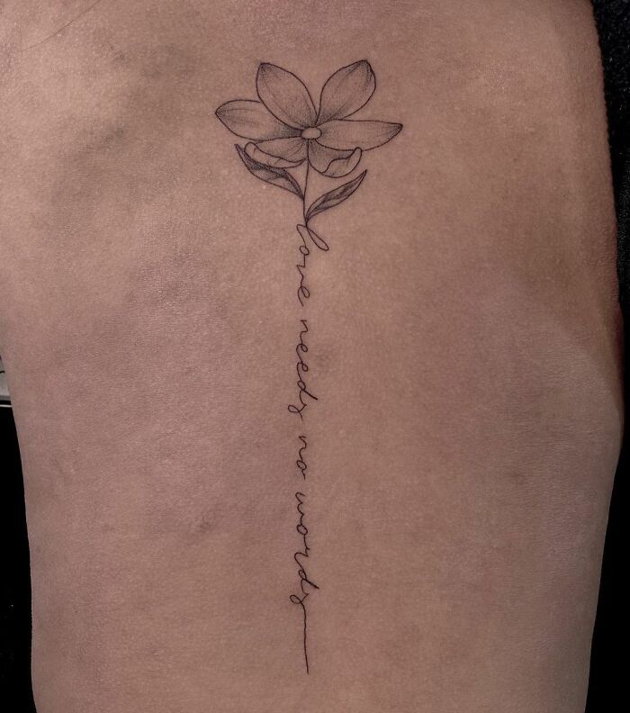 Lettering and flower tattoo on spine