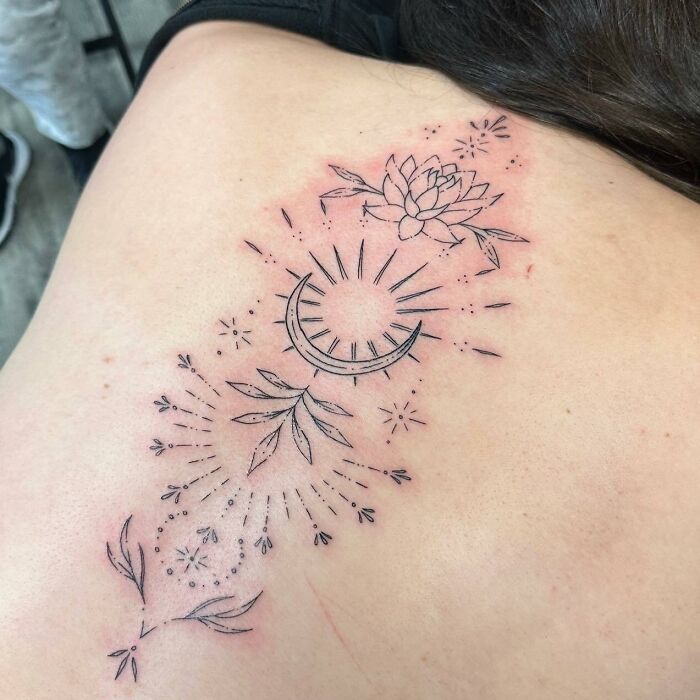 Elegant spine tattoo with sun, moon, and floral design detail.
