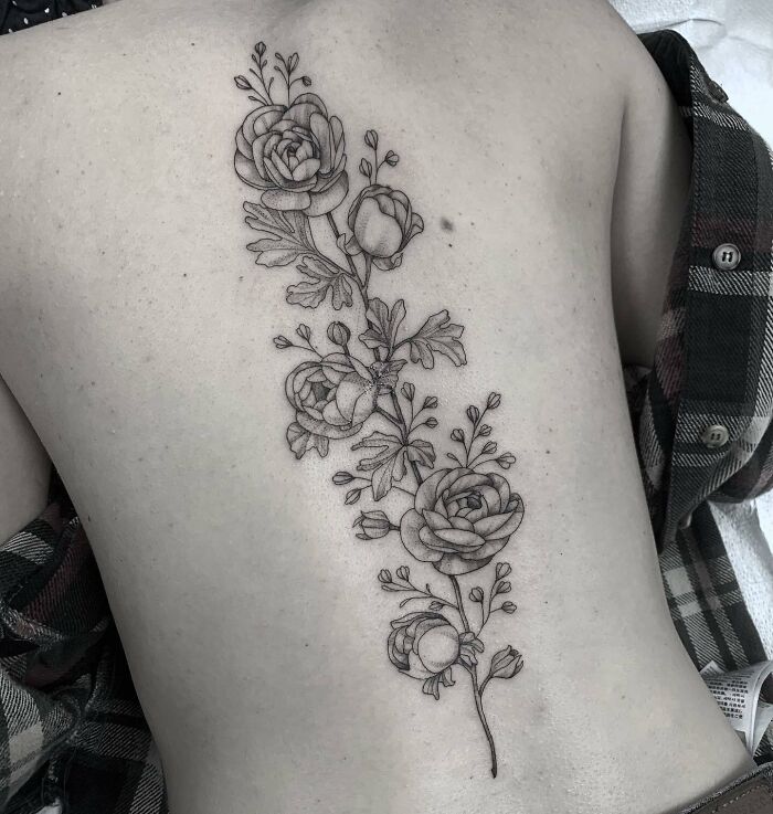 Vertical branch with many flowers spine tattoo