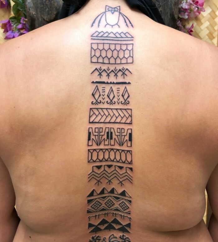 Abstract tribal spine tattoo design on a person's back, featuring geometric and organic patterns.
