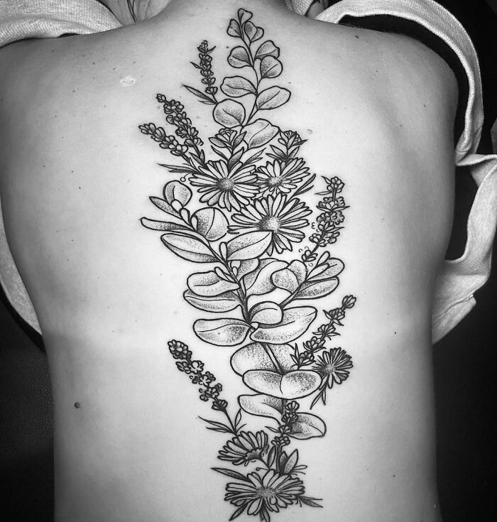 Floral spine tattoo design featuring intricate leaves and flowers, showcasing elegance and artistry on the back.