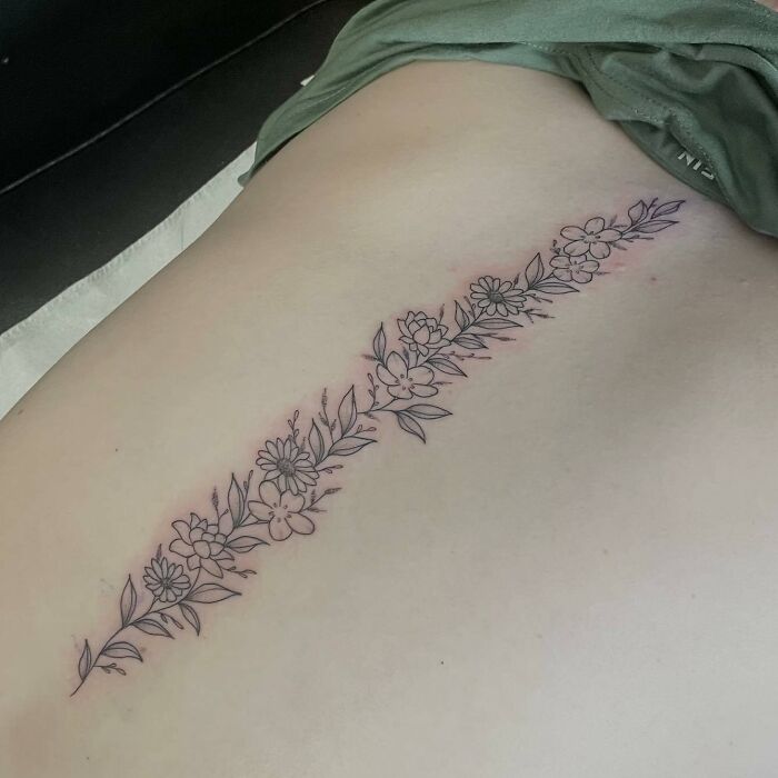 Floral spine tattoo showcasing intricate design, freshly inked on skin.