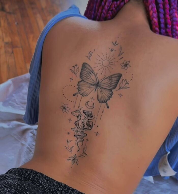 Butterfly mushroom spine tattoo on woman’s back
