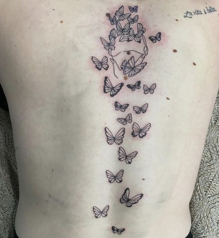 Many black butterflies tattoo on spine