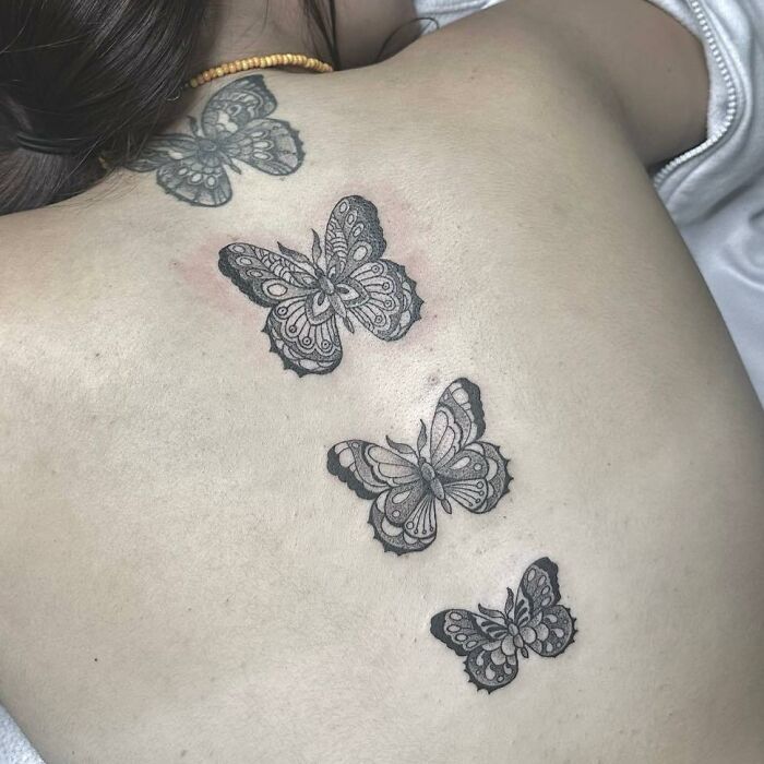 Butterfly spine tattoos on a person's back, showcasing intricate designs on smooth skin.