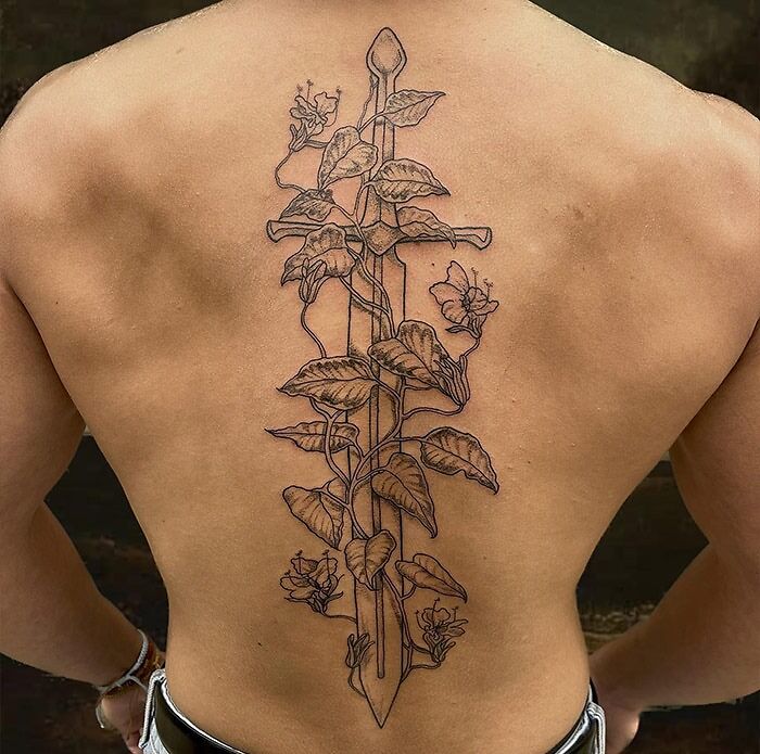 Large black sword and botanics tattoo on spine
