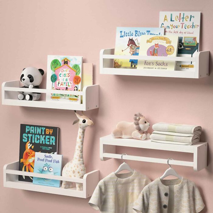 Four white wooden wall-mounted floating shelves with books and toys in it