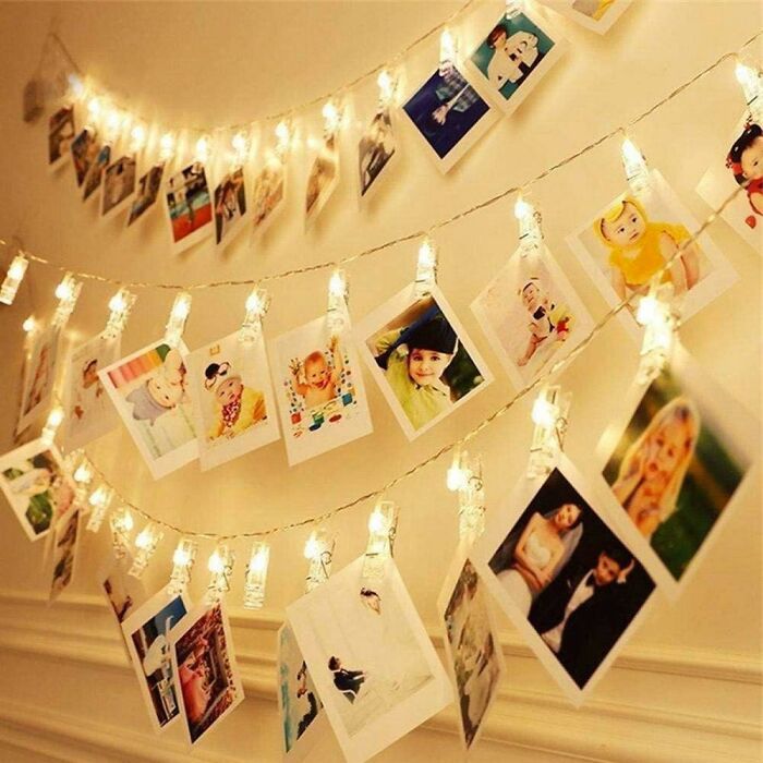 LED fairy string lights hanging on the wall with many photos clipped