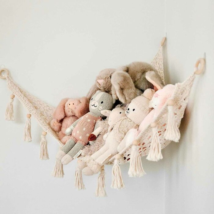 Hanging buttercream macrame corner hammock with plush toys in it
