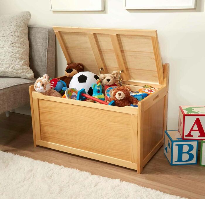 Light wooden box storage with an open cover and many plush toys in it